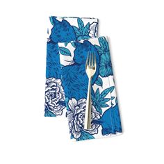 two napkins with blue and white flowers on them, one has a fork in it