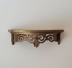 an ornate gold shelf on a white wall