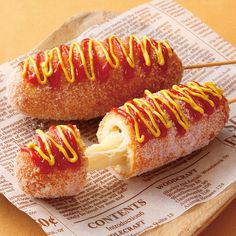 two doughnuts covered in ketchup and mustard on top of a newspaper