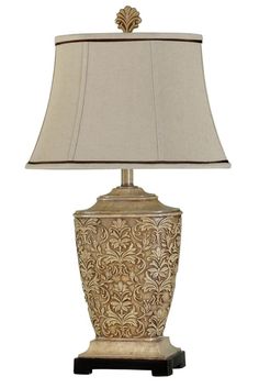 a lamp that is sitting on top of a wooden stand with a white and gold shade