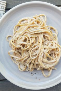 a white plate topped with pasta on top of a wooden table