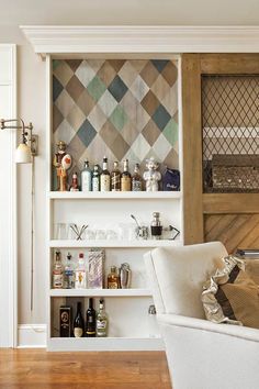 a white chair sitting in front of a book shelf filled with bottles and liquor on top of a hard wood floor