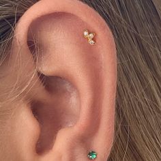 a close up of a person's ear with two different colored stones on it