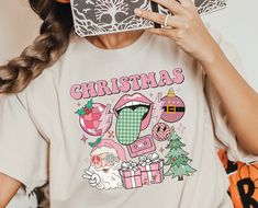 "Embrace the festive spirit in style with our vibrant collection featuring the \"Pink Christmas Vibes Shirt,\" \"Retro Christmas Shirt,\" \"Pink Santa Sweatshirt,\" \"Funny Merry Christmas Shirt,\" and the \"Santa Tree Ornaments Presents Shirt.\" Each piece encapsulates the joy and playfulness of the holiday season, offering a unique blend of retro vibes and merry cheer. Perfect for those who adore a touch of humor and a splash of color in their holiday wardrobe, our collection is designed with high-quality materials and a comfortable fit, ensuring a jolly experience for any occasion.  Materials → All our simple color ones like White and Black are 100% Cotton. → All our Heathered Colors are cotton/polyester blend and they are super comfy soft! → Soft and High-Quality Fabric → Sueded Jersey Funny Merry Christmas, Retro Christmas Shirt, Santa Tree, Merry Christmas Funny, Pink Santa, Santa Sweatshirt, Merry Christmas Shirts, Christmas D