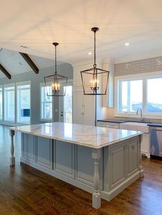 a large open kitchen with an island in the center and two pendant lights hanging from the ceiling