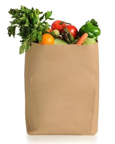 a brown paper bag filled with lots of fresh fruits and vegetables on top of a white background