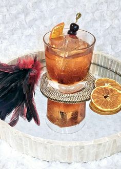 an old fashioned drink with orange slices and garnishes on a glass tray