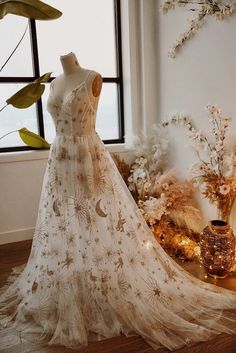 a dress is on display in front of a window with flowers and plants around it