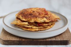 a stack of pancakes sitting on top of a white plate next to a wooden cutting board