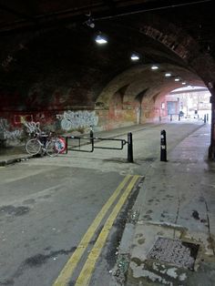 an empty parking garage with graffiti on the walls and sidewalk next to bike racks in it