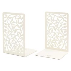 two white metal bookends with leaves and vines on the sides, one has a hole in the middle