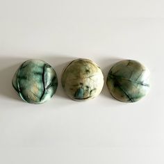 three green stones sitting next to each other on a white surface