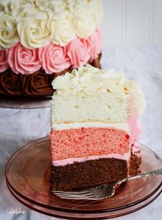 there is a piece of cake with pink and white frosting on the plate next to it