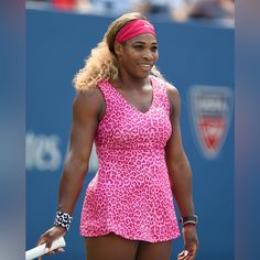 a female tennis player in a pink leopard print dress and headband smiles at the camera