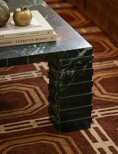 a marble coffee table with two books on top and an apple sitting on top of it