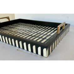 a black and white striped tray with handles on the bottom is sitting next to a chair