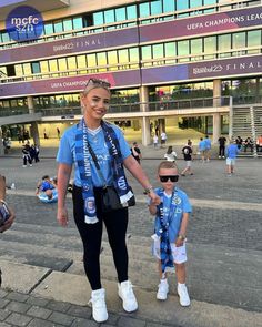 a woman and two small children walking in front of a building with people standing around