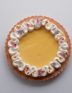 there is a pie with flowers on it and white frosting in the middle, sitting on a table