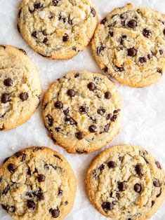 six chocolate chip cookies sitting on top of white paper