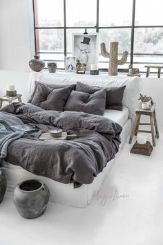 a bed sitting in the middle of a room with lots of pillows on top of it