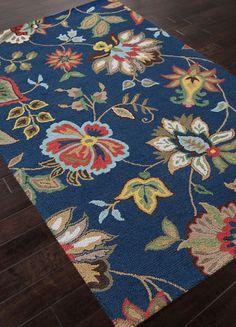 a blue rug with colorful flowers on the floor and wood floors in front of it