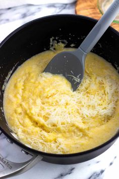 a skillet filled with cheese on top of a counter next to a spatula