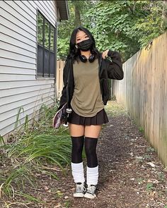 a woman wearing knee high socks and boots standing in front of a house with her hands on her head