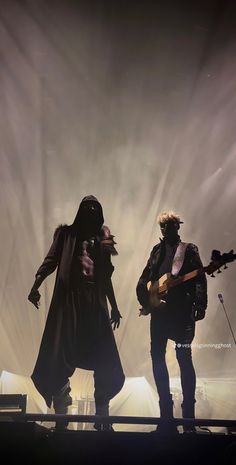 two people standing on stage with guitars in their hands