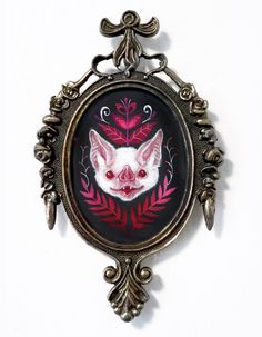 an ornate frame with a pink and white cat on it's face is hanging from the wall