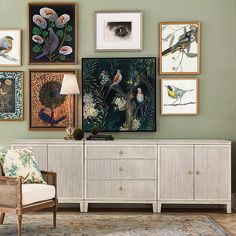 a living room with green walls and pictures on the wall, including a white sideboard