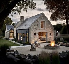 a stone house with a fire pit in the front yard and patio area next to it