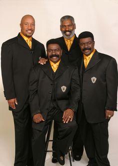 a group of men standing next to each other wearing black suits and yellow vests