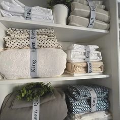 the shelves are filled with towels and other items in white linens, including blankets