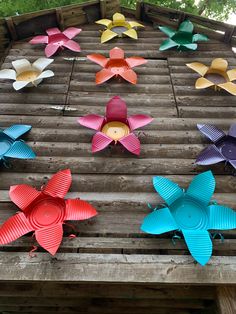 colorful paper flowers are arranged on a wooden platform