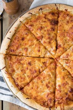 a cheese pizza cut into eight slices on top of a wooden table with napkins