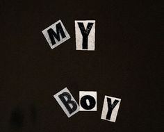 the word my boy written in cut out letters on a black surface with white paper