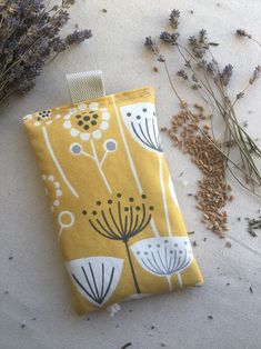 a yellow and white flowered pouch sitting on top of a table next to dried flowers