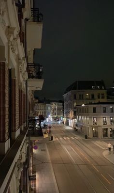 an empty city street at night with no cars on the road and buildings in the background