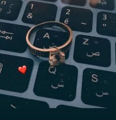 a ring sitting on top of a computer keyboard next to a red heart shaped object