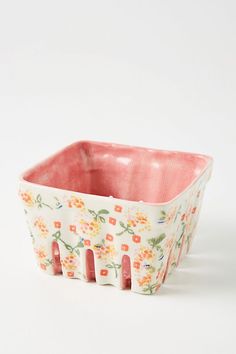 a pink and white flowered dish on a white surface