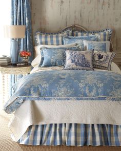 a bed with blue and white comforters in a bedroom next to a window,