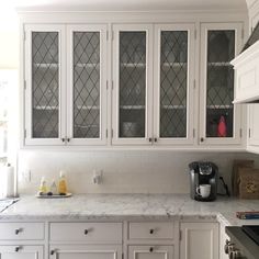 a kitchen with white cabinets and marble counter tops