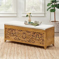 a wooden bench sitting on top of a rug next to a potted plant and window