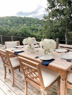 a wooden table topped with white flowers and plates