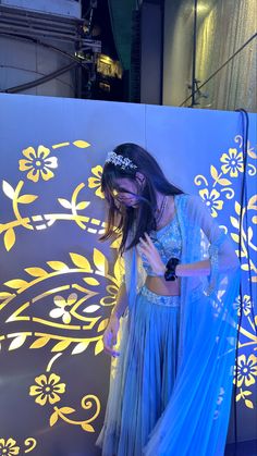 a woman in a blue dress standing next to a wall