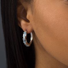 Express your modern style with these gorgeous gemstone hoop earrings. Crafted in sterling silver, each sophisticated hoop showcases three 6.0 x 4.0mm oval-shaped sky-blue topaz alternating with sculpted "X" shapes. Buffed to a brilliant luster, these earrings secure with latch backs. Stone Hoop Earrings, Gemstone Hoop Earrings, Sky Blue Topaz, Three Stone, Blue Topaz, Sterling Silver Earrings, Sky Blue, Modern Style, Topaz