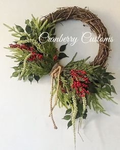 two wreaths with red berries and greenery hanging on the wall next to each other