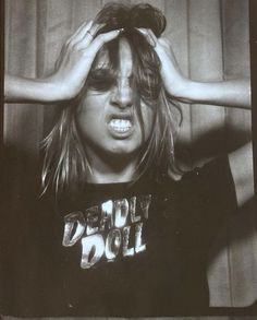 a black and white photo of a woman holding her hair in front of her face