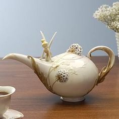 a white teapot sitting on top of a wooden table