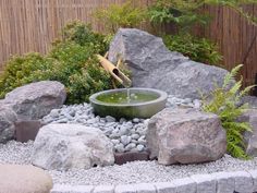 a small garden with rocks and water features an outdoor fountain in the center, surrounded by greenery